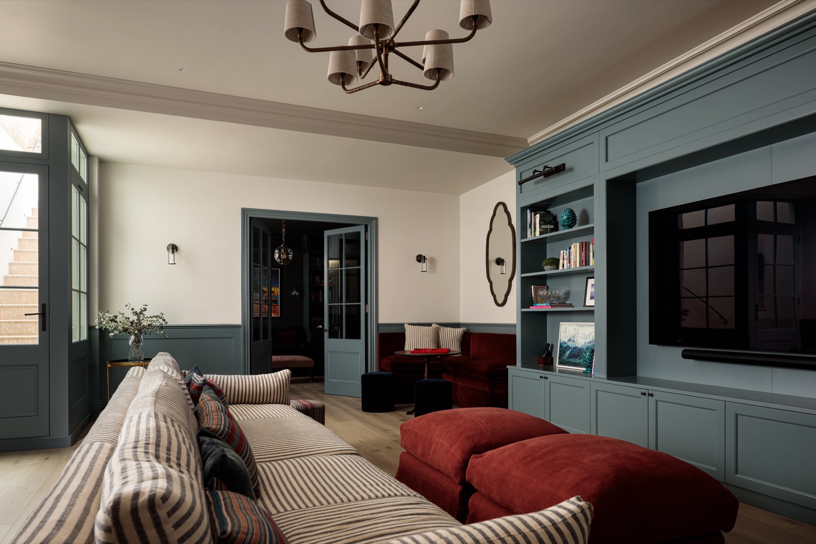 A basement family room with built-in blue joinery, under a house in Parsons Green
